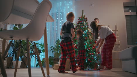 A-family-with-two-children-decorate-a-Christmas-tree-on-Christmas-Eve.-Father-and-mother-with-children-prepare-for-new-year-and-Christmas-decorating-house.-High-quality-4k-footage